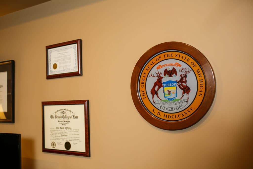 John G McNally Law Degree and other awards and accreditations hanging on wall along with The Great Seal Of The State Of Michigan