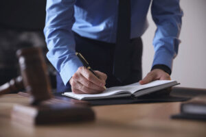 Lawyer standing over a desk while writing in a notebook.